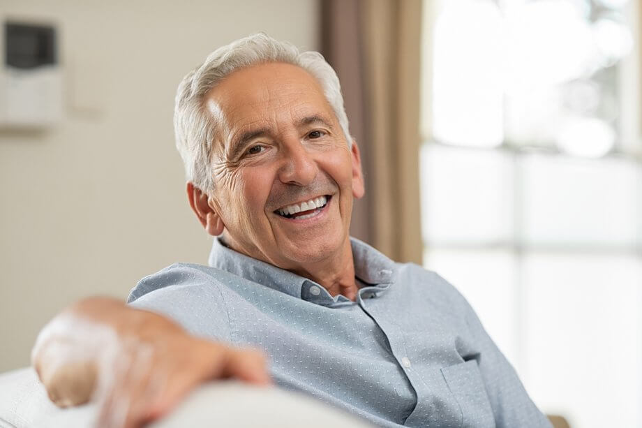 white haired man smiling at camera