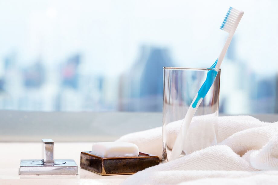 white towel, toothbrush resting in glass and soap dish with square white soap