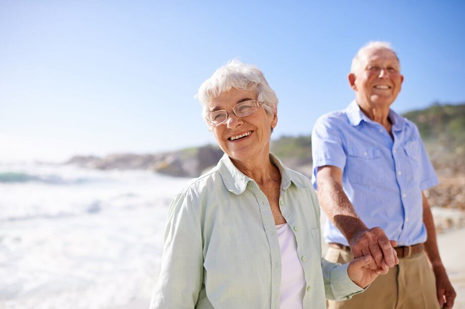 smiling mature couple hold hands on the beach