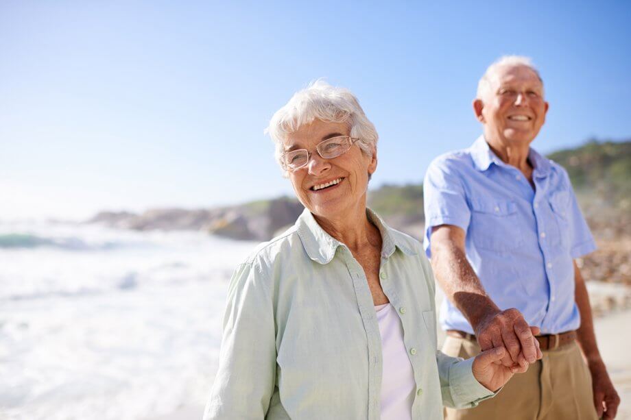 smiling mature couple holding hands on a beach